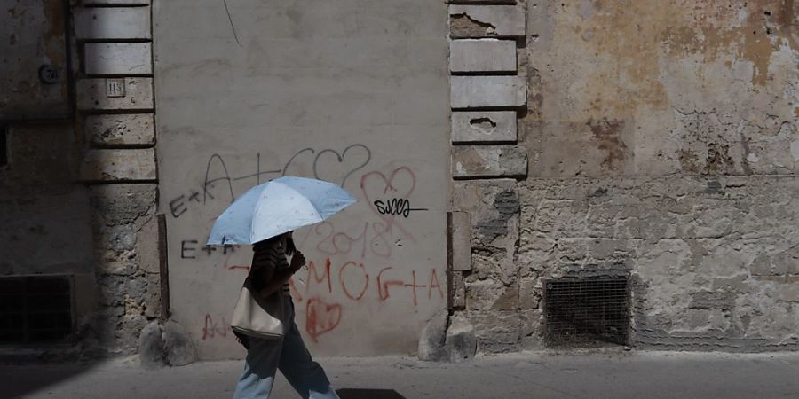 Eine Frau schützt sich in Taranto (I) mit einem Schirm vor der Hitze. 2023 gab es in Italien 12'750 Hitzetote.