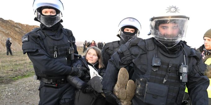Greta Thunberg scheint zu lächeln, als sie von den Polizisten abgeführt wird. Greta Thunberg