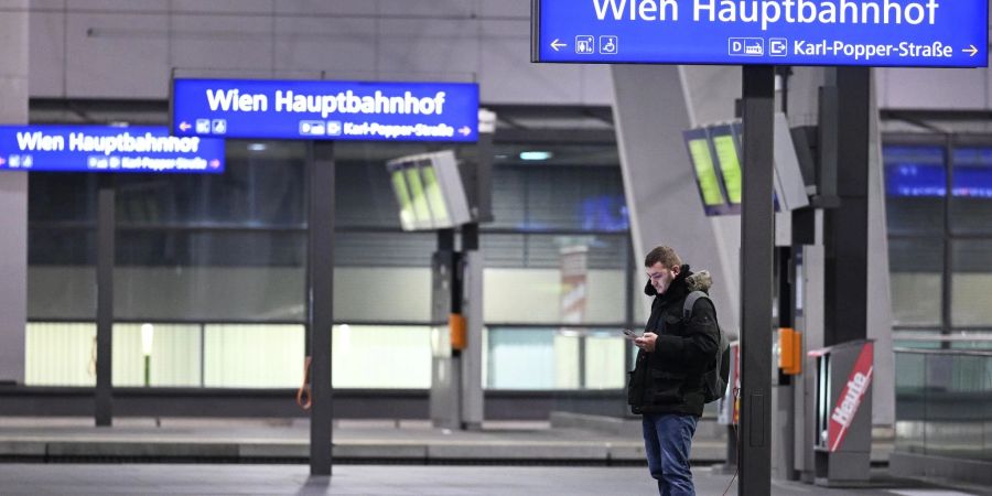 Ein Mann blick auf sein Smartphone an einem Bahnsteig im Hauptbahnhof Wien.