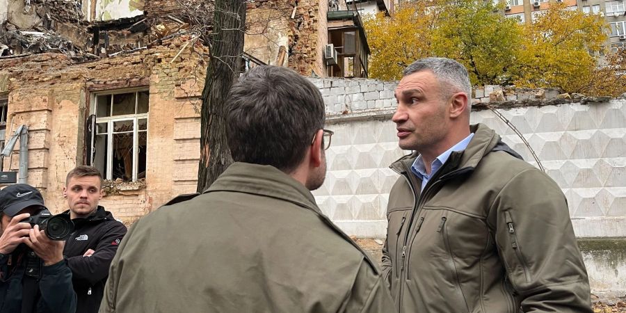 Bundesjustizminister Marco Buschmann (FDP, vorn) spricht bei einem Besuch in der Ukraine mit Kiews Bürgermeister Vitali Klitschko vor einem im Oktober 2022 durch einen Drohnenangriff zerstörten Haus.