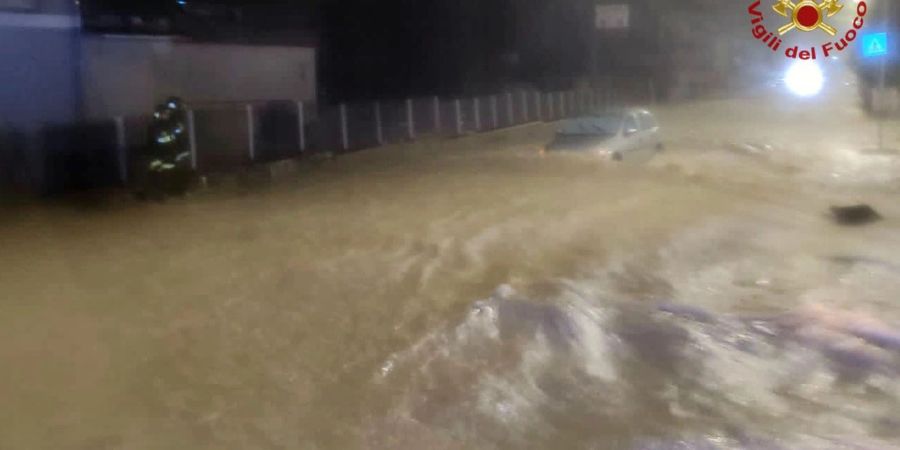 Auf einer überfluteten Strasse treibt ein Auto durch die Wassermassen.