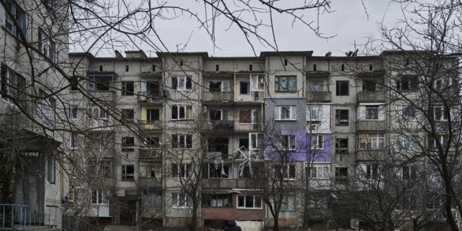 Ein Zivilist geht in Soledar an schwer beschädigten Wohngebäuden vorbei. Angehörige der berüchtigten russischen Söldnertruppe Wagner haben die Eroberung des Ortes verkündet. Foto: Libkos/AP/dpa