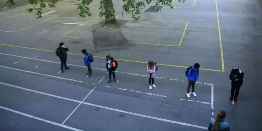 Schüler auf einem Schulhof mit Abstandsmarkierungen