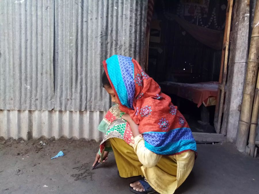 Ein Mädchen in Bangladesh spielt am Boden