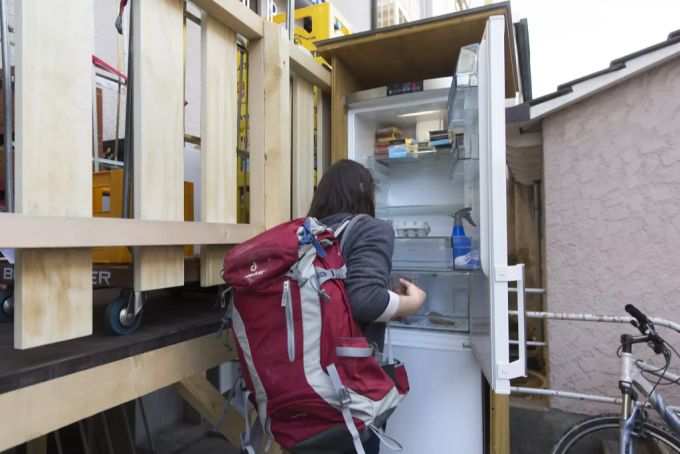 Eine Anwohnerin bedient sich an einem Gemeinschaftskühlschrank. Gemeinschaftskühlschrank für Spenden