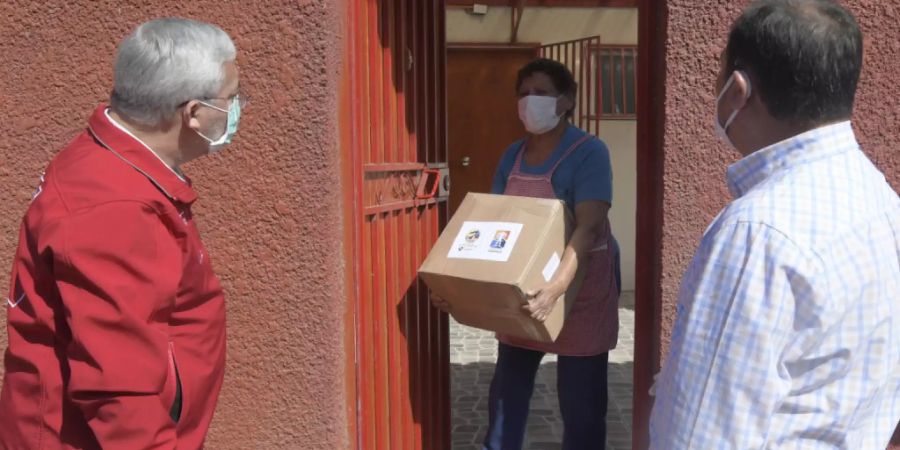 Eine Frau in Iquique bekommt ein Lebensmittelpaket. Angesichts der Corona-Krise hat die Regierung in Chile Zehntausende Lebensmittelpakete an Bedürftige verteilt. Foto: Cristian Vivero Boornes/Agencia Uno/dpa