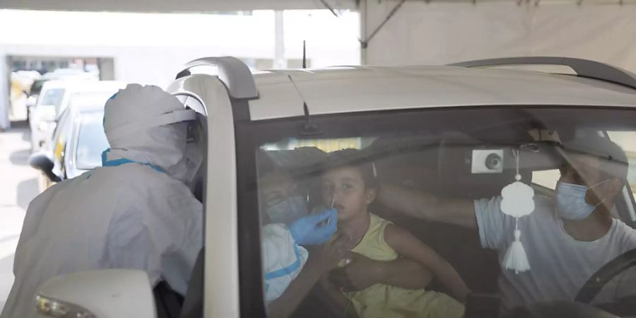 Ein medizinischer Mitarbeiter entnimmt einem Mädchen an einer Drive-Thru-Station für Covid-19-Tests in Tel Aviv einen Abstrich. Foto: Sebastian Scheiner/AP/dpa