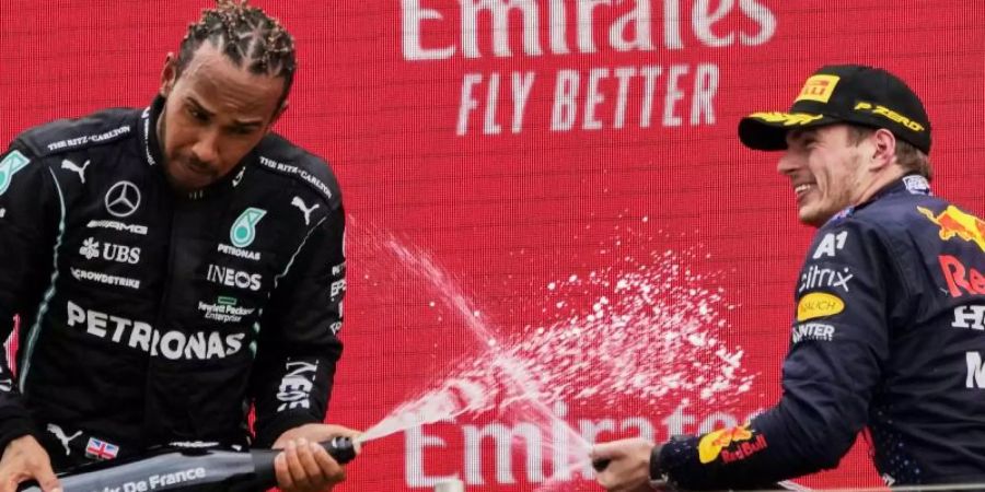 Sieger Max Verstappen (r) und der Zweitplatzierte Lewis Hamilton lassen auf dem Podium den Champagner spritzen. Foto: Francois Mori/AP/dpa