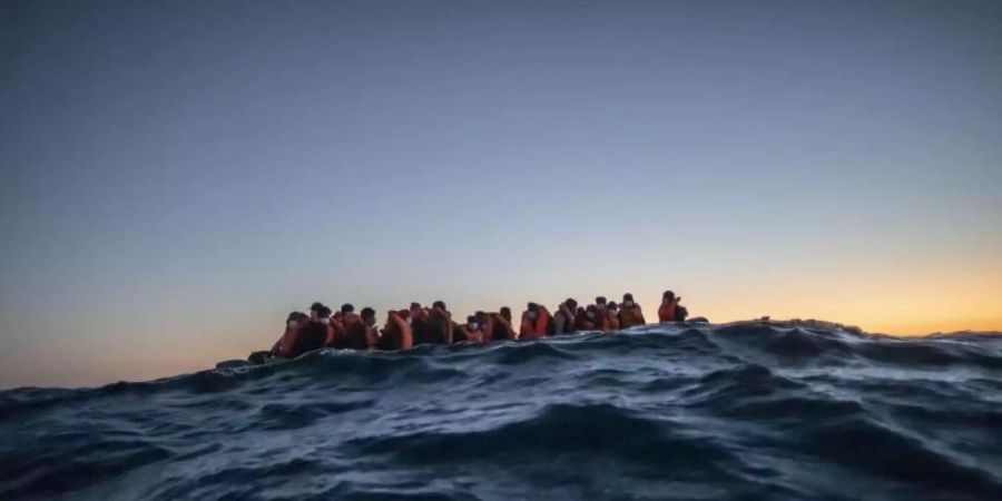 Migranten aus verschiedenen afrikanischen Nationen warten in einem Boot vor der libyschen Küste im Mittelmeer auf Helfer. Foto: Bruno Thevenin/AP/dpa