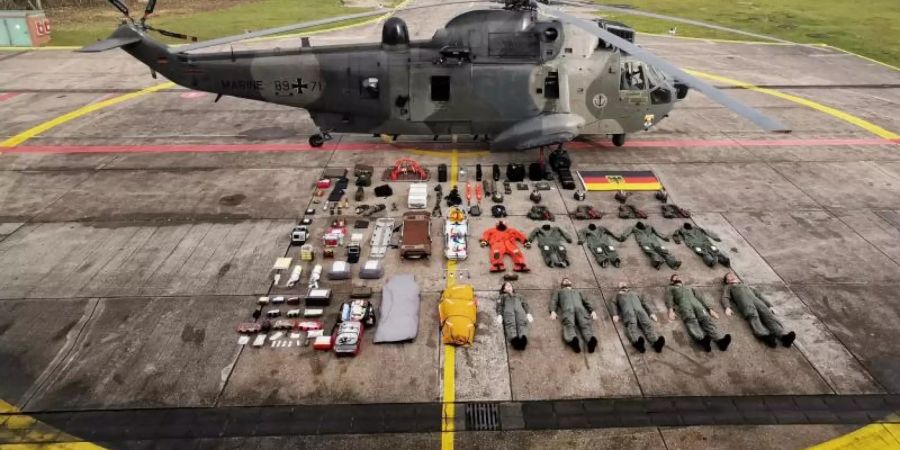 Fünf Seenotretter samt Ausrüstung liegen neben dem Rettungshelikopter SeaKing MK41. Foto: Team No.1/Deutsche Marine, Marinefliegergeschwader 5/dpa