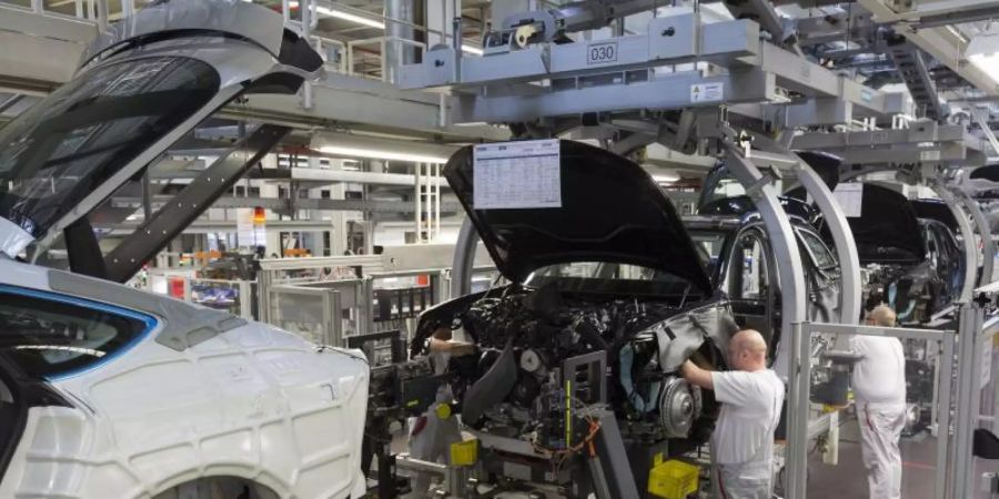 Werksmitarbeiter montieren in einer Produktionshalle von Audi bei der sogenannten «Hochzeit» den Motor an einem A6. Foto: Ronald Wittek/dpa