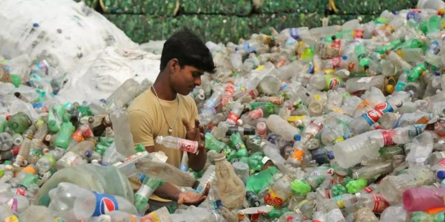 Ein Arbeiter sortiert Plastikflaschen, bevor sie in einer industriellen Anlage am Stadtrand recycelt werden. Indiens Premierminister Modi hat dem Einwegplastik den Kampf angesagt. Foto: Channi Anand/AP/dpa