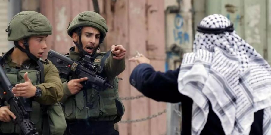 Ein Mann streitet in Hebron im Westjordanland mit israelischen Soldaten. Foto: Wisam Hashlamoun/Zuma Press/dpa/Archiv