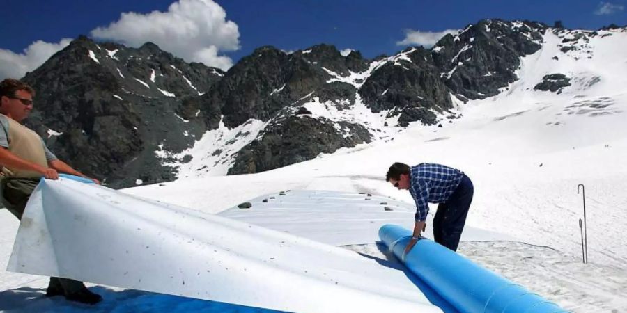 Retten, was zu retten ist: Helfer rollen im Hochsommer schützende Planen auf dem Tortin-Gletscher in der Schweiz aus. Foto: epa Keystone Olivier Maire/epa Keystone/dpa