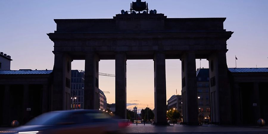 Berlin: Am frühen Morgen ist der Himmel hinter dem Brandenburger Tor erhellt (Archivbild).