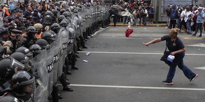 Eine Frau wirft während eines regierungskritischen Protestes in Buenos Aires einen Müllsack auf die Polizei. Foto: Natacha Pisarenko/AP/dpa Proteste in Buenos Aires