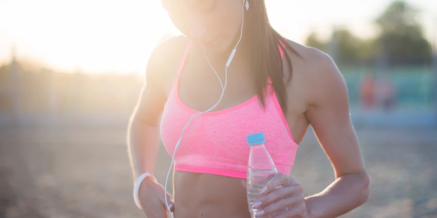 Frau mit Sport-BH und Wasserflasche