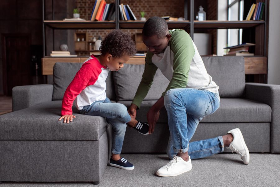 Vater zieht seinem Sohn die Schuhe an