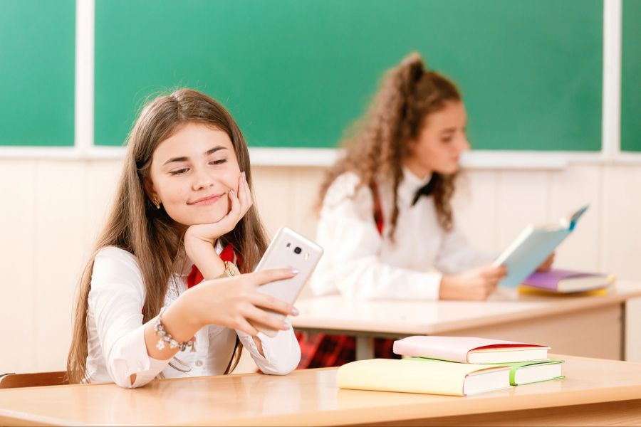Klassenzimmer Mädchen Smartphone Bücher