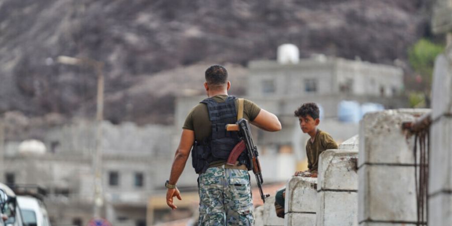 dpatopbilder - Ein bewaffneter Mann geht auf dem Sirah-Fischmarkt in Aden an einem Jungen vorbei. Foto: Abdulnasser Alseddik/AP/dpa