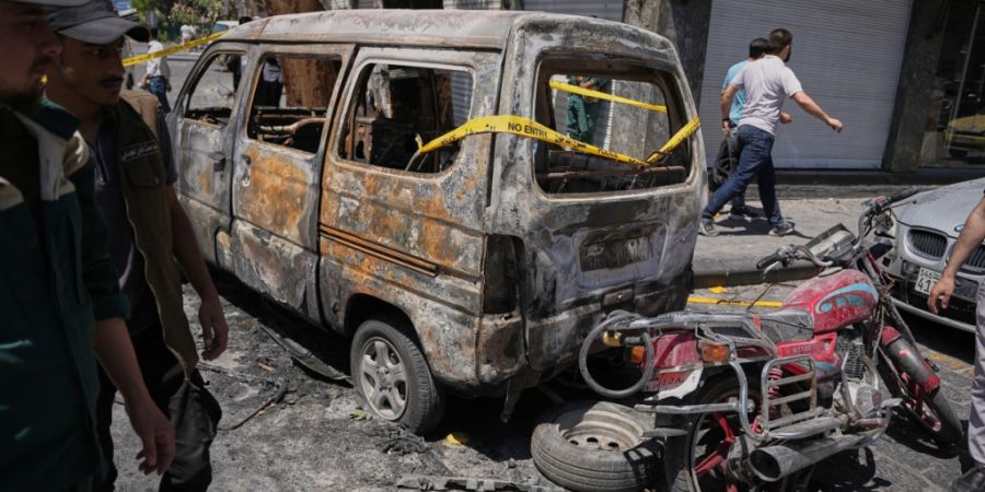 Syrische Sicherheitskräfte untersuchen ein ausgebranntes Fahrzeug in Damaskus, nachdem zuvor zwei Explosionen die Gegend erschüttert hatten. Foto: Omar Albam/AP/dpa