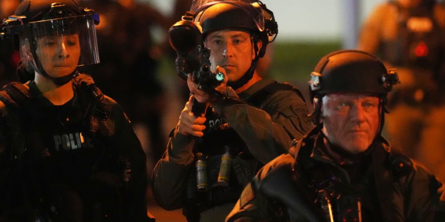 ARCHIV - Ein Beamter richtet seine Waffe auf Demonstranten vor dem Delaney Hall Detention Center in Newark, New Jersey. Die Vereinten Nationen zeigen sich angesichts der Zahl der Todesf...