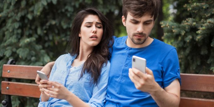 Emotionale Untreue gilt im Allgemeinen auch als eine Form des Betrugs. Eifersüchtige Frau mit ihrem Partner auf einer Bank