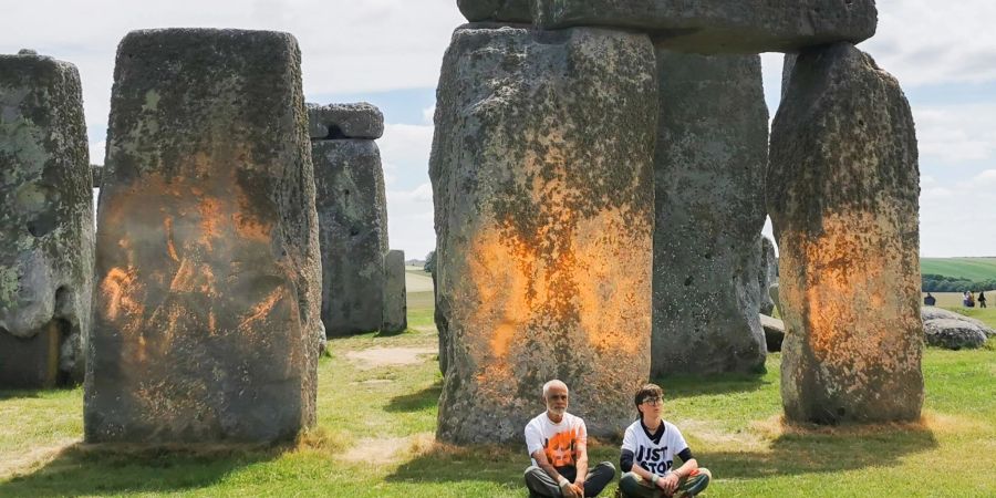 Demonstranten von «Just Stop Oil» sitzen vor dem Steinmonument Stonehenge, das sie zuvor mit orangener Farbe besprüht haben.