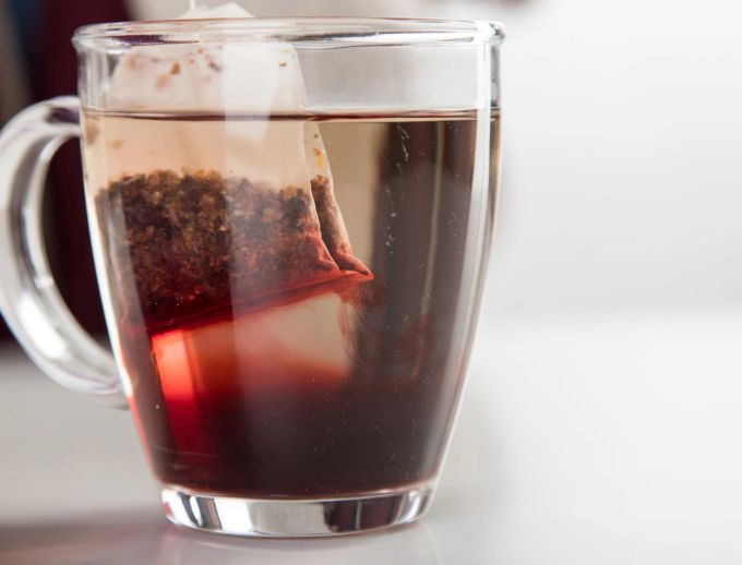 Gerade im Sommer ist Cold Brew Tee erfrischend. Doch nicht alle Sorten sollten kalt aufgebrüht werden. Manchmal ist abkühlen lassen und dann trinken besser. Teebeutel rot Glas Wasser Tee