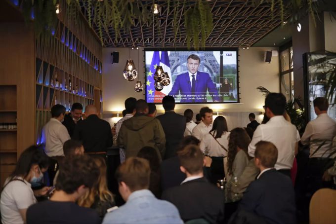 In einer Pariser Bar verfolgen die anwesenden Gäste gespannt, wie Präsident Macron die Impfpflicht verkündet. macron bar tv