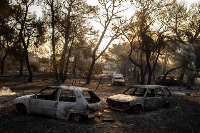 Ausgebrannte Fahrzeuge stehen vor einem Haus nach einem Waldbrand in der Region Varibobi im Norden Athens. Foto: Angelos Tzortzinis Waldbrände in Griechenland