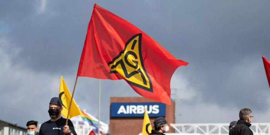 Beschäftigte des Airbus-Werkes in Finkenwerder schwenken Fahnen der IG Metall (Mai). Foto: Daniel Reinhardt/dpa