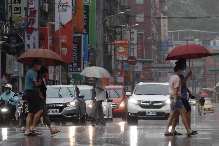 Menschen gehen durch verregnete Strassen in Taiwan.