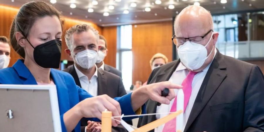 Peter Altmaier (r, CDU), Bundesminister für Wirtschaft und Energie, sieht sich das Modell einer möglichen Raketen-Startplattform der GOSA in der Nordsee an. Foto: Bernd von Jutrczenka/dpa