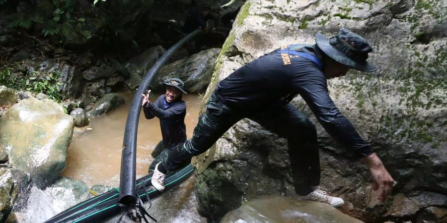 Thailändische Soldaten bringen Schläuche, mit denen das Wasser aus der Höhle befördert werden soll.