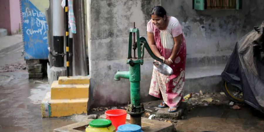 Eine Frau in Indien sammelt Trinkwasser.