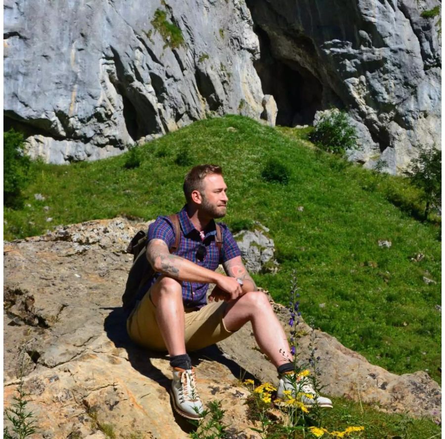 Marco Fritsche sitzt lässig auf einem Stein.