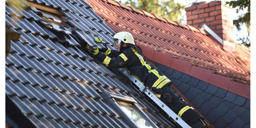 Auch umliegende Häuser sind durch die Explosion beschädigt worden. Eine Feuerwehrfrau entfernt von einem lose Dachziegel.