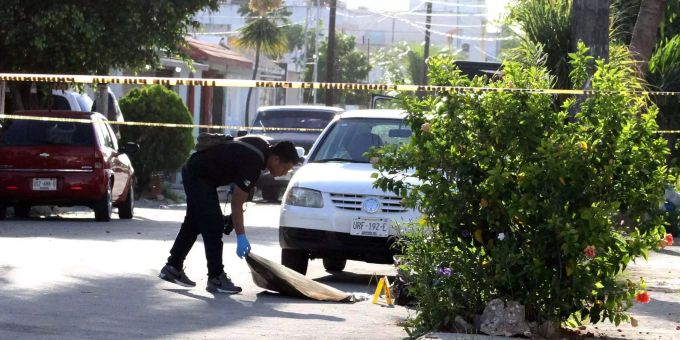 Ein Polizist deckt im mexikanischen Cancun die Überreste einer Leiche zu. Ein Polizist deckt im mexikanischen Cancun die Überreste einer Leiche zu.
