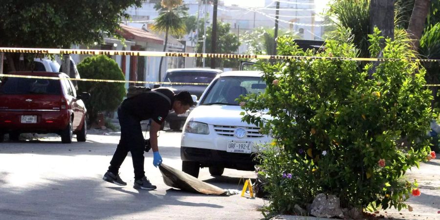 Ein Polizist deckt im mexikanischen Cancun die Überreste einer Leiche zu.