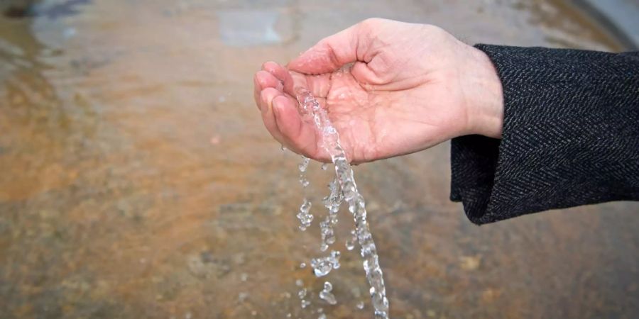 Ein Mann wäscht sich die Hände am Trinkbrunnen in Zürich.