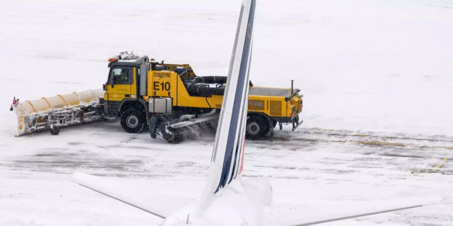 Schnee wird hinter einer Maschine vom Flugplatz Genf geräumt.