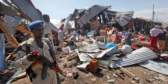Ein somalischer Polizist steht neben zerstörten Geschäften nach einem Attentat der Al Shabaab. 20 Tote bei Al-Shabaab-Angriff