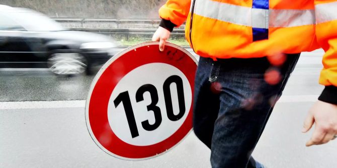 Ein Arbeiter hat ein Strassenschild in der Hand.
