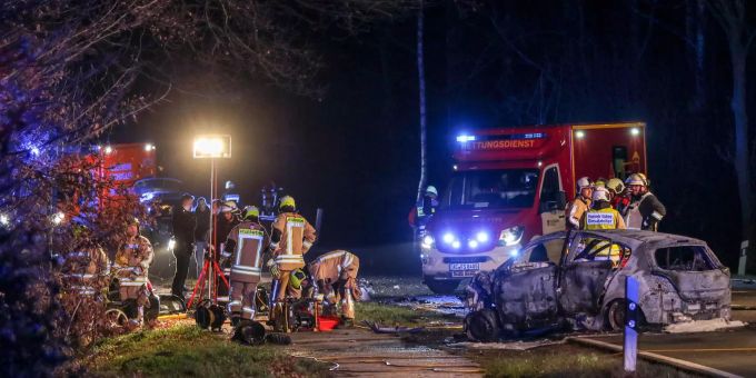 Bei dem Unfall, bei dem ein Auto vollständig ausbrannte, kamen fünf Menschen ums Leben. Feuerwehrleute stehen an den zwei Fahrzeugen.
