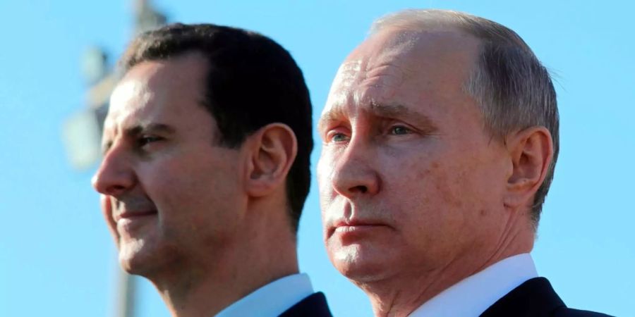 Der russische Präsident Wladimir Putin (r) und der syrischen Präsident Baschar al-Assad schauen sich am 11.12.2017 in Hmeimim (Syrien) auf der Luftwaffenbasis Hmeimim eine Truppenübung an.