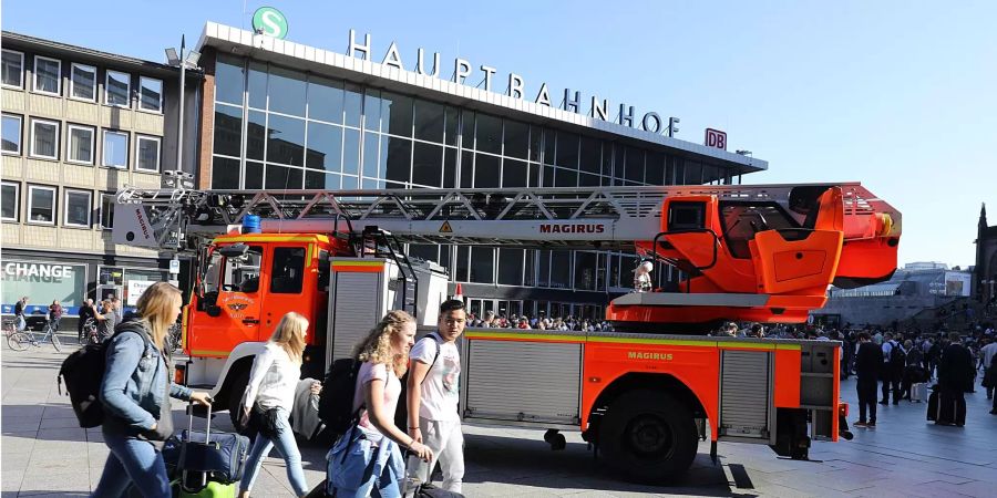 Reisende gehen mit ihren Koffern vor dem Kölner Hauptbahnhof.