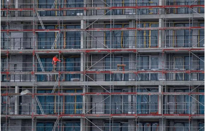 Gebäude in der Bauphase mit Gerüsten und einem Bauarbeiter darauf - Keystone Gebäude in der Bauphase mit Gerüsten und einem Bauarbeiter darauf - Keystone