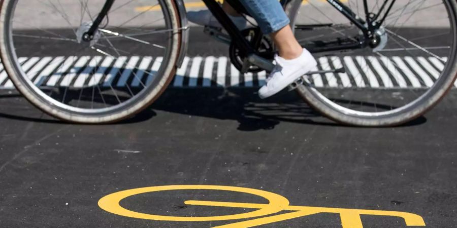 Eine Frau fährt mit ihrem Velo auf einem Rad- und Fussweg.