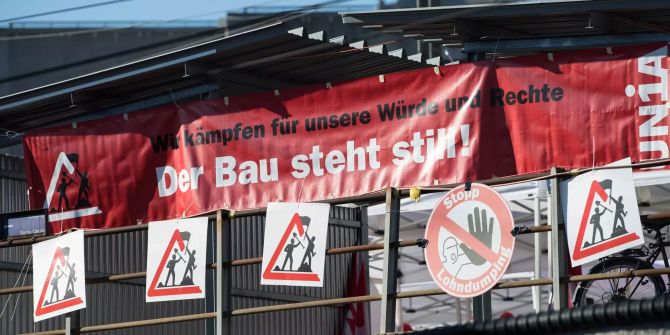 Plakate und Transparente hängen bei einer Demonstration von Bauarbeitern auf der Schützenmatte in Bern.